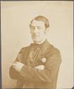 [Man with arms folded, cigar in left hand]