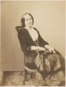 [Woman seated in chair with fringe]