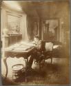 [Man wearing beret working at desk]