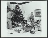 Father taking home movie of wife and children opening Christmas presents