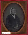 [Elderly woman with bonnet and lace gloves]