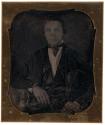 [Seated man in suit]