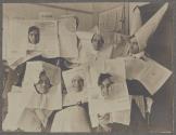 [Group of six men with faces in holes cut in newspapers]