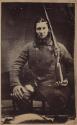[Man with rifle and dog in lap]