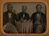 [Three men seated at round table]