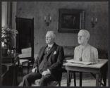 George Eastman posing beside bust