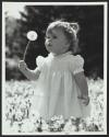 Girl blowing on dandelion in field