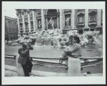 Man photographing woman beside public fountain