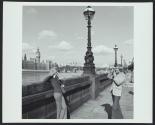 Man photographing woman beside the River Thames in London