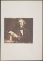 [Seated man with hands on book]