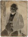 [Man, seated with a cane]