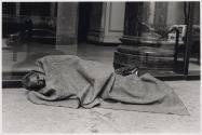 [Homeless man asleep on sidewalk]