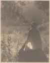 [Marjorie Rambeau sitting in a field of flowers]