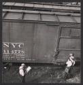 [Two men in front of a railroad car]