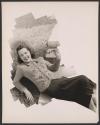 [Woman modeling embroidered sweater, perched on grass, collage effect]