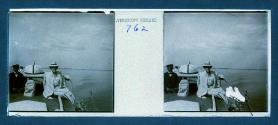 [Woman posing next to captain(?) of boat]