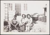 [Boy and two women seated on front steps]