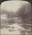 [Bridge and buildings by a creek]