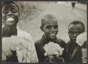 Three small Kikuyu boys sell sweet-peas along a road in Nairobi, Kenya.