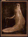 [Bride standing next to table]