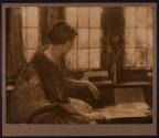 [Seated woman in front of windows]