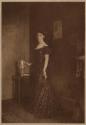 [Woman standing by vase]