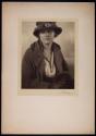 [Woman in hat holding muff]