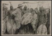 Johnsons posing with shield and native tribesmen, African Safari