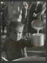 [Boy receiving cup of milk, refugee camp near Athens, Greece]