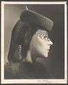 [Fashion photograph: Profile head of a model wearing a hat with veil and a snood]