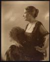 [Woman holding feather fan]