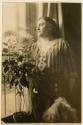 [Clara Steichen standing next to window with flowers, Voulangis, France]