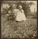 [Baby in Grass with Chair and Bottle]