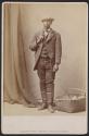 [Man standing with a basket near his feet]