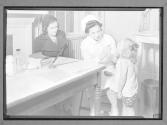 [Nurse at Desk with Child and Parent]