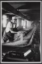 Our daily bread: Man grabbing grain from conveyor belt, Pillsbury Company, Springfield, Illinois