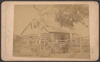 [Robert Orrock and family in front of log cabin]