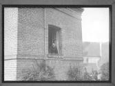 Old Woman Looking Out Window Brick Building