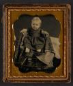 [Baby seated on small blanket-covered chair]