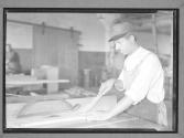 Man with guarded saw and stick to feed saw