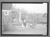 [Women Holding Children Outside Home]
