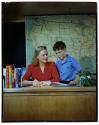 [Teacher and student at desk (advertisement)]