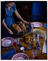 [Woman placing platter of meat on table (advertisement)]