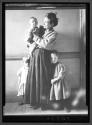 [Woman Holding Child, Two Children Nearby]