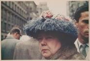 [Woman wearing blue feather hat with pink roses]