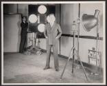 Rudy Vallee, in front of bank of photo electric cells as he's televised