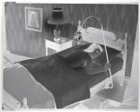 [Woman lying in bed under lamp]