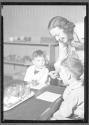 [Two Children, Woman administering Medicine]