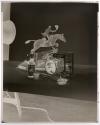 [Whiskey bottle and glass, figurine of a man riding a horse, and books (Hunter)]