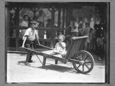 [Child Pushes Child on Cart]